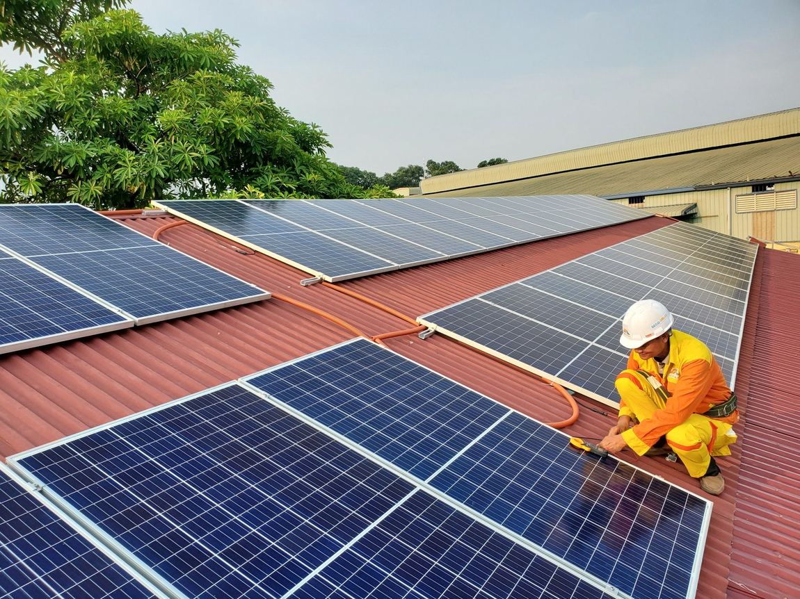 Technician inspecting and testing a rooftop solar panel array during routine maintenance