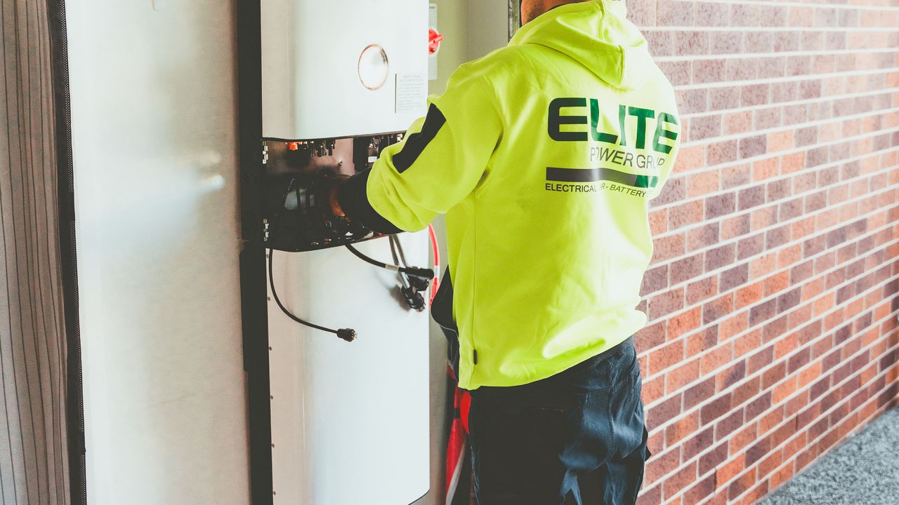 A technician servicing a wall-mounted home solar battery storage unit