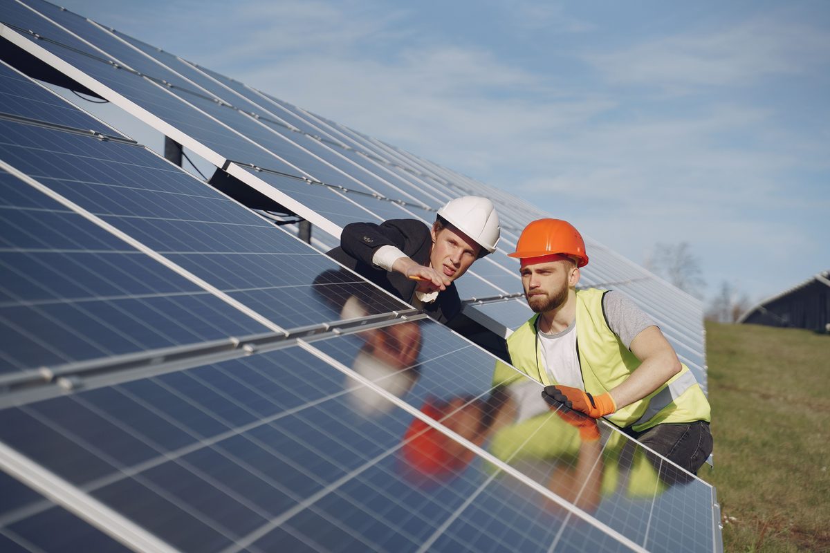 Two technicians inspecting a ground-mounted solar array together before commissioning