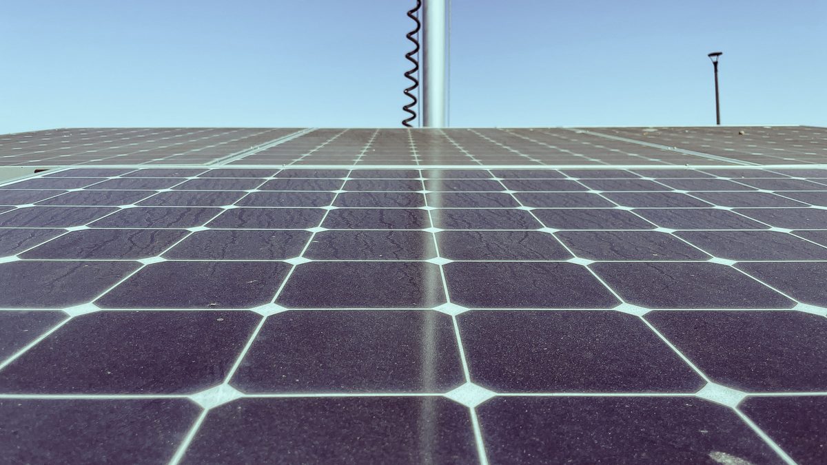 Close-up of a monocrystalline solar panel showing its cells and busbars against a blue sky
