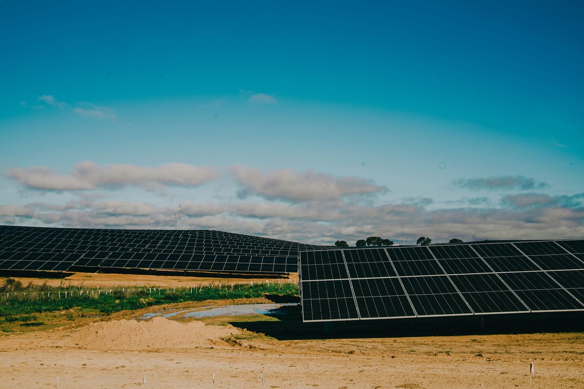Large ground-mounted solar array in a hot, dry desert landscape under a bright sky