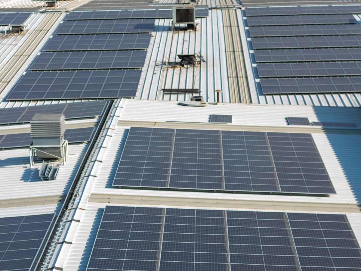 Large rooftop solar panel array on commercial buildings, showing panels weathering years of outdoor exposure